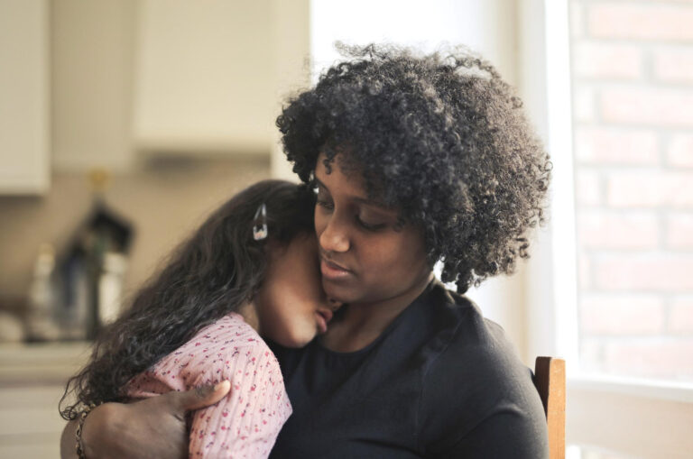 shallow-focus-tired-multi-racial-kid-hugging-her-black-mother-home